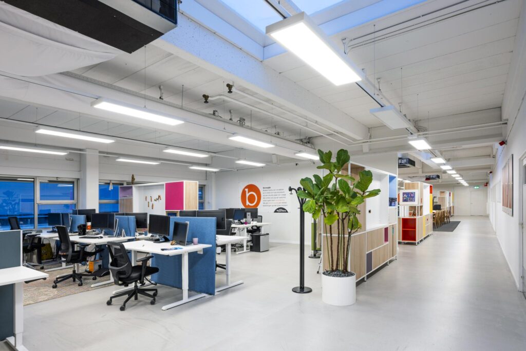 Modern kantoorinterieur aan de Van der Madeweg met bureaus, open werkplekken en een grote kamerplant.